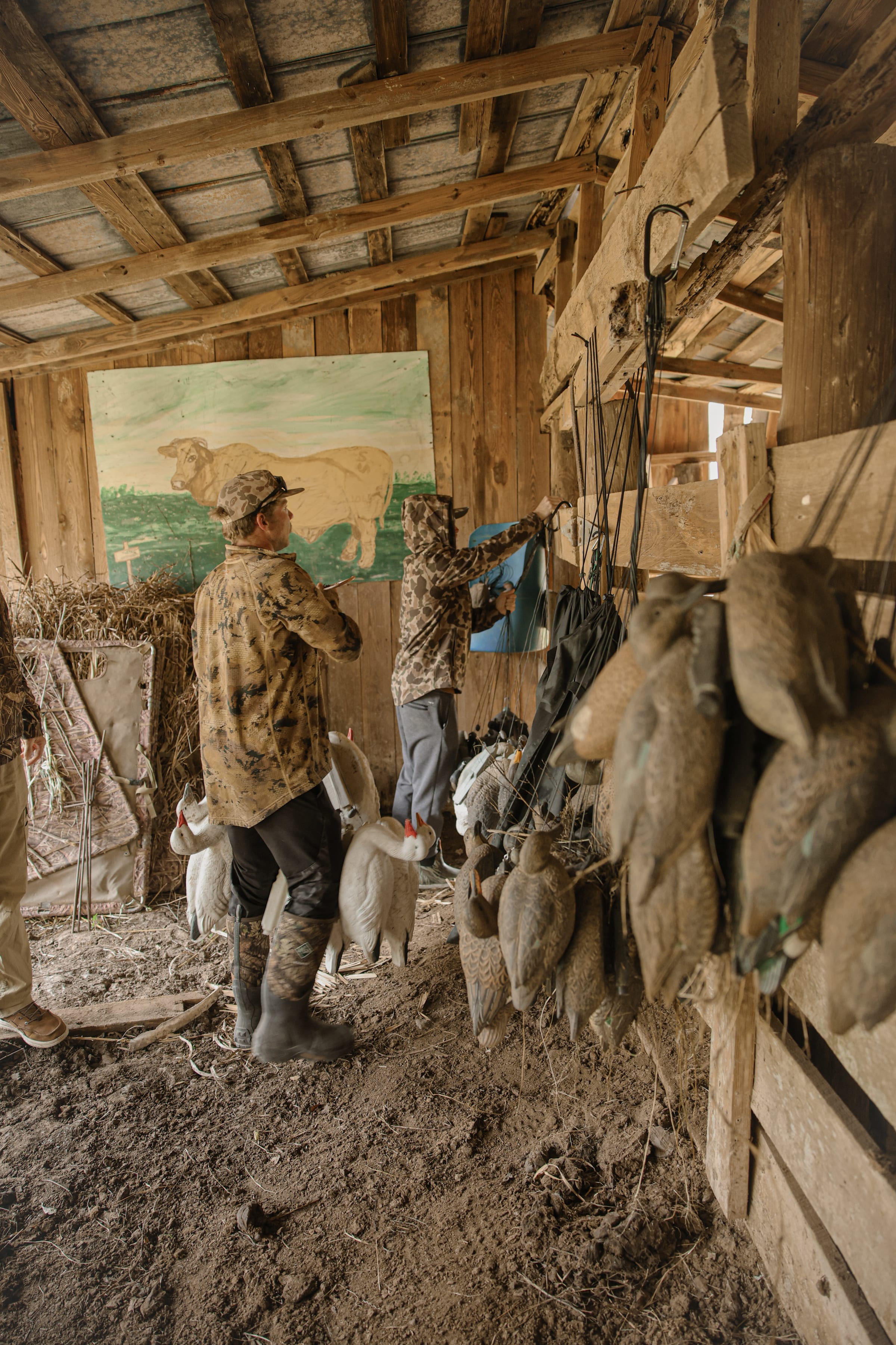 Barn interior with wooden beams, hanging hunting decoys, painted hog mural