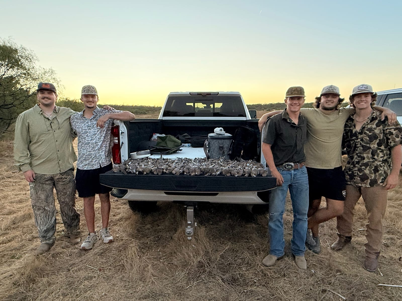 Group hunting doves at tailgate, sunset sky
