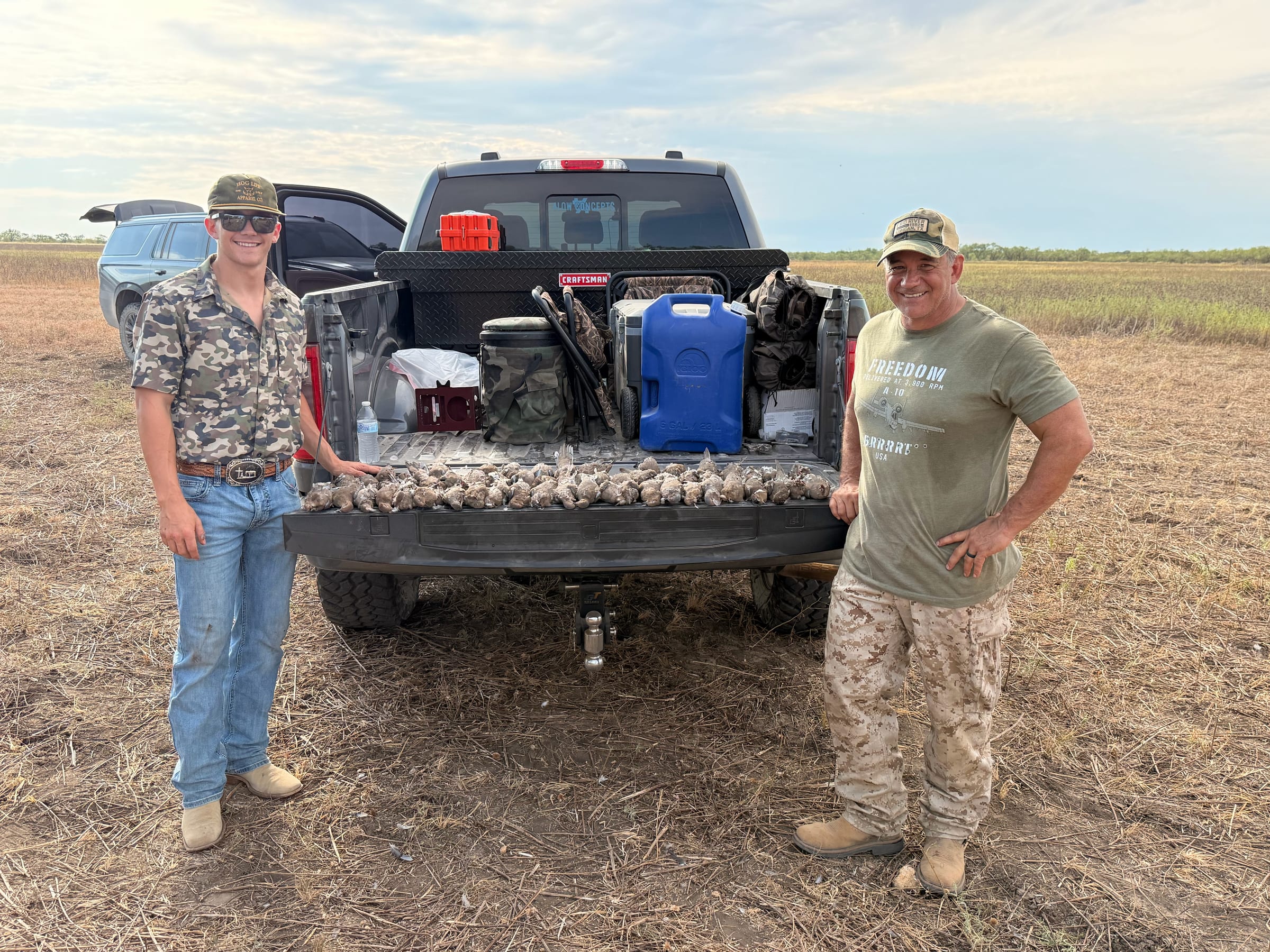 Two people with truck bed doves laid out, sunset background