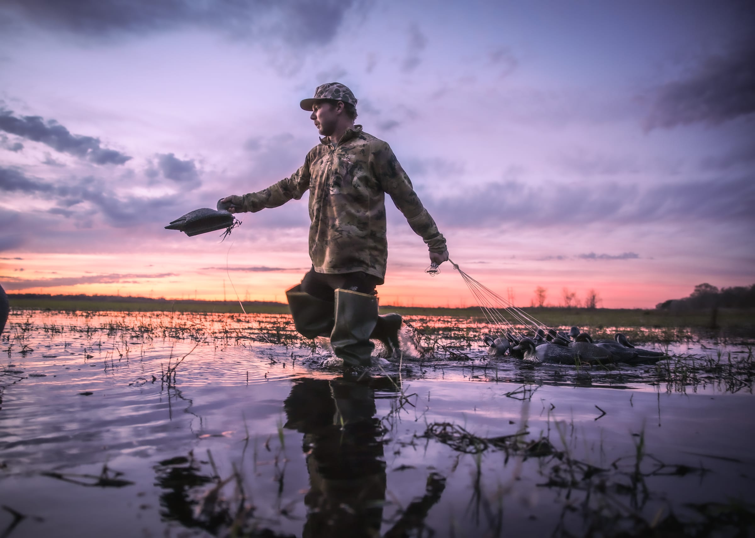 Person carrying hunting gear at sunset